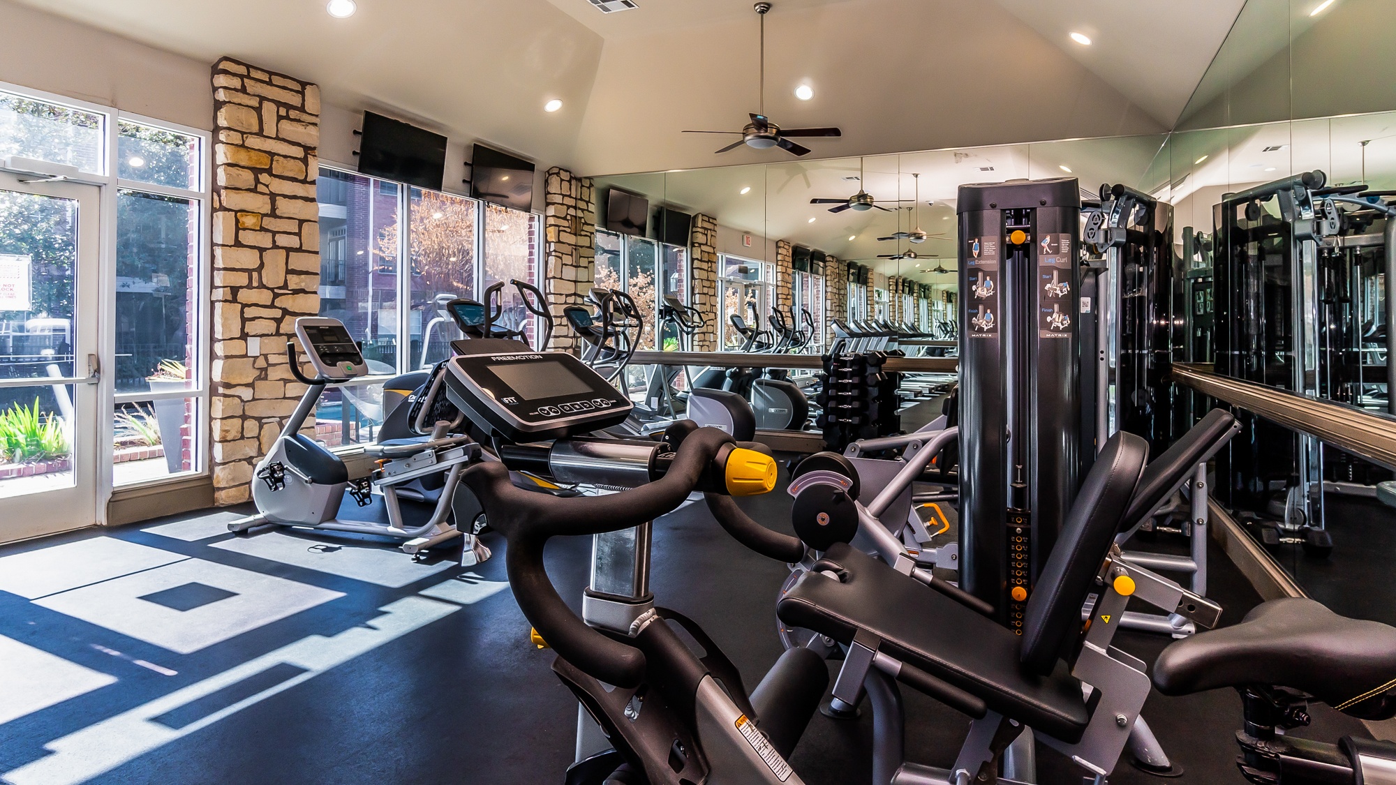 A gym with a variety of exercise equipment including treadmills, stationary bikes, and weight machines.